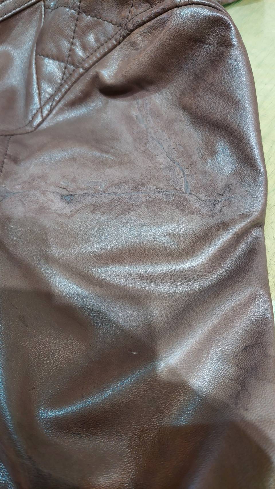 革ジャンパーの袖を補修している途中の写真。大きな隙間が塞がり、つないだ境目が見える状態
